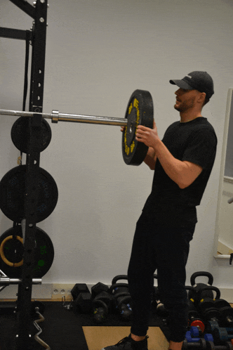 a man is lifting a barbell with a yellow weight plate that says ' stamina ' on it