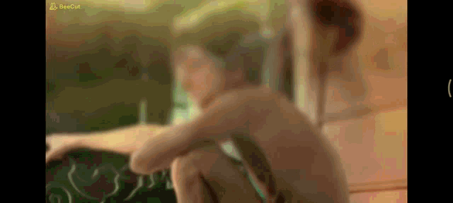 a blurred image of a naked woman sitting on a bed with a sign that says ' bengal ' on it