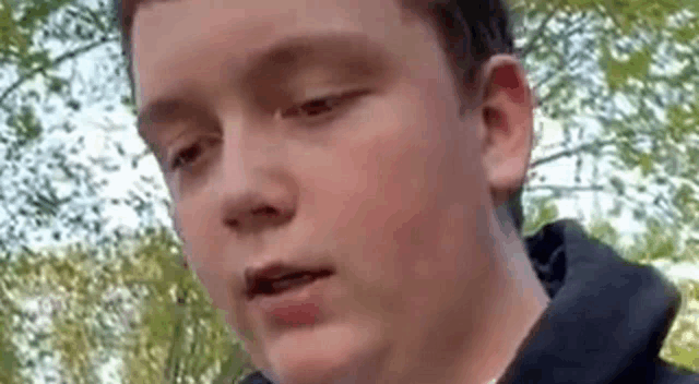 a young boy wearing a black hoodie is making a funny face .