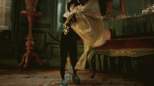a woman in a white dress is dancing in a room with a red couch