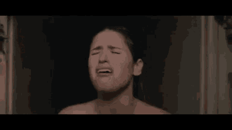 a woman is crying in a shower with her eyes closed and her mouth open .
