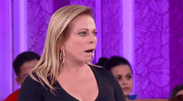 a woman in a black shirt and hoop earrings is making a funny face .