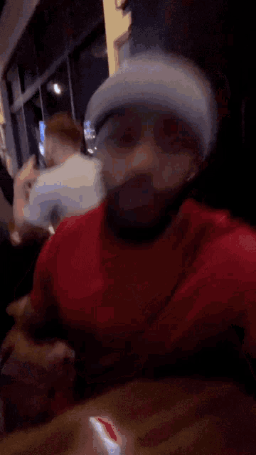 a man wearing a red shirt and a gray beanie is taking a selfie