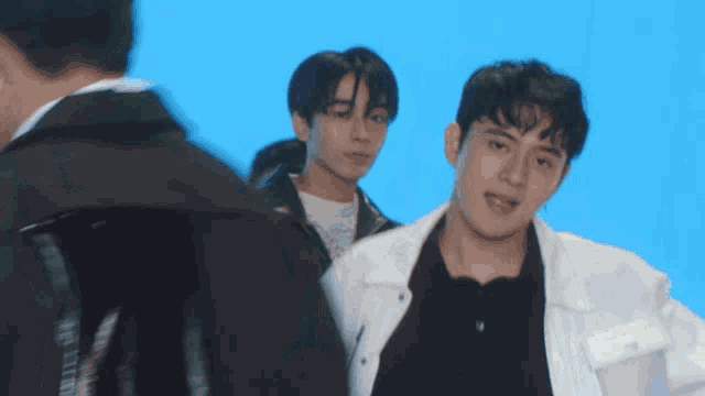 a group of young men are standing in front of a blue background