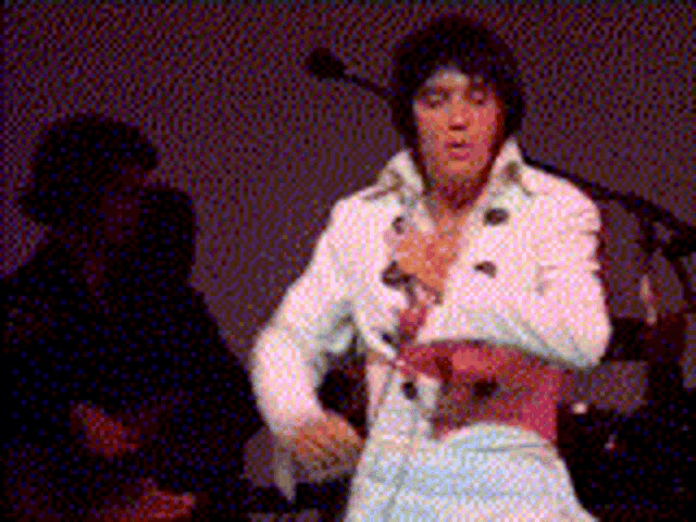 a man in a white suit is singing into a microphone