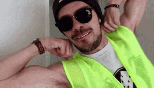 a man with a beard and sunglasses is wearing a neon yellow vest and a black hat .