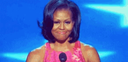 michelle obama is standing in front of a microphone on a stage .