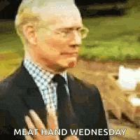 a man in a suit and tie is making a gesture with his hands .
