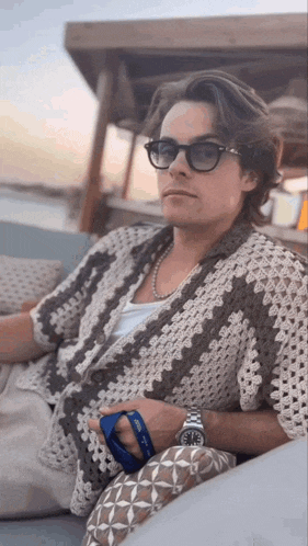 a man wearing sunglasses and a watch is sitting on a bench