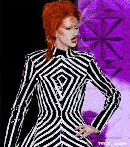 a woman with red hair is wearing a black and white striped jacket with a diamond pattern
