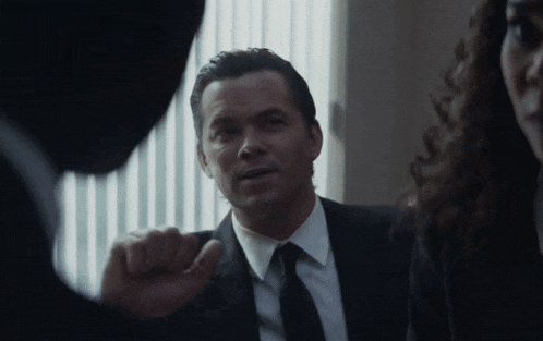 a man in a suit and tie talks to another man