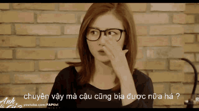 a woman wearing glasses is covering her nose with her hand