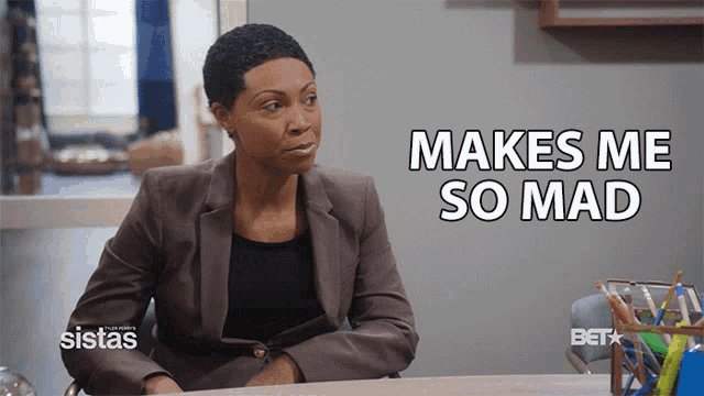 a woman sitting at a desk with the words " makes me so mad "