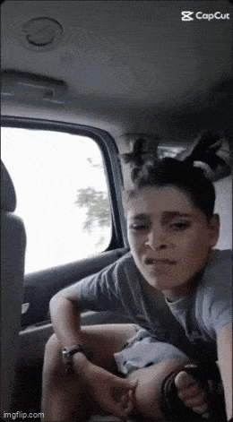 a woman is sitting in the back seat of a car with her hair in pigtails .