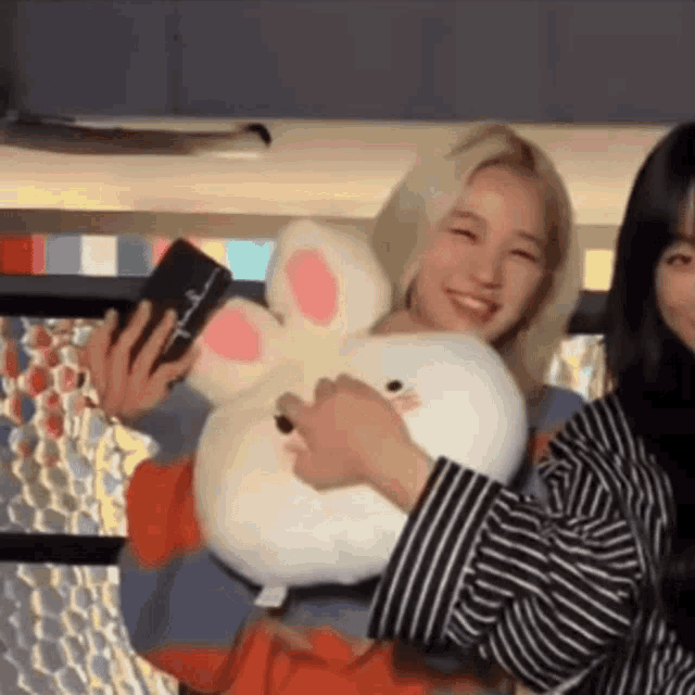 a woman is holding a stuffed rabbit and a cell phone .