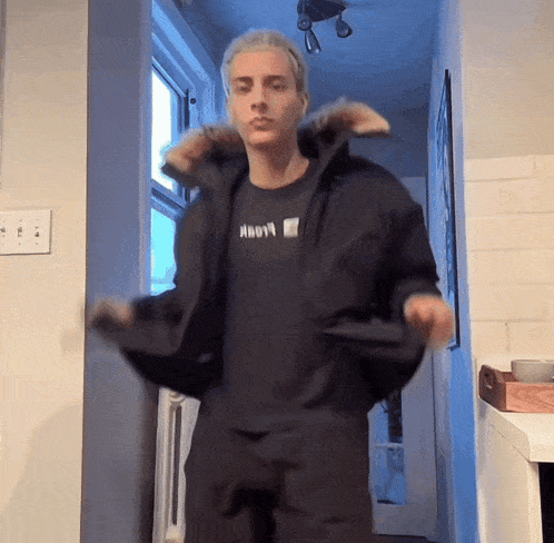 a man wearing a black jacket and a black t-shirt with the word hoovy on it
