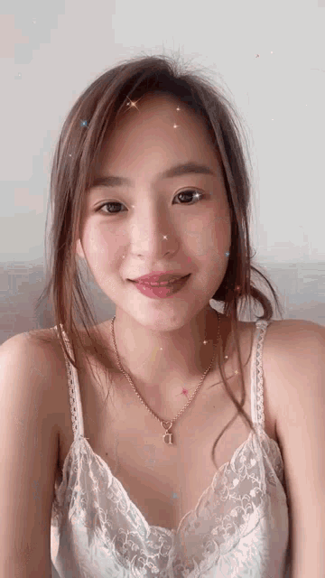 a young woman wearing a white lace top and a gold necklace