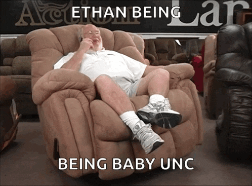 a man sits in a recliner with the words " ethan being being baby unc " written below him