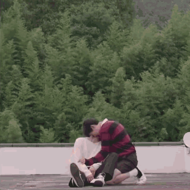 a man is kneeling down next to a woman on a rooftop in front of trees .