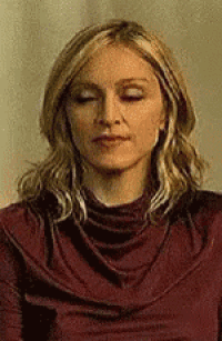 a woman with her eyes closed is wearing a red shirt .