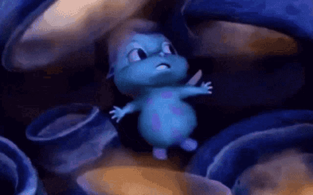 a blue and purple cartoon character is standing in a dark room surrounded by blue objects .