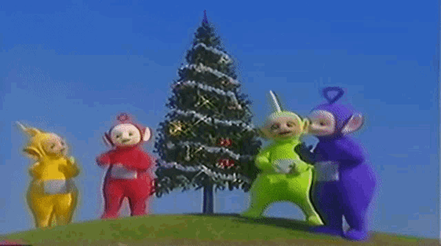 four teletubbies are standing in front of a christmas tree
