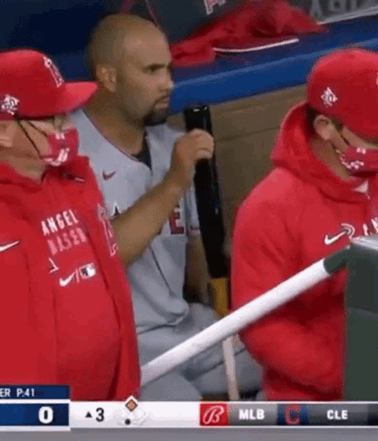 a group of baseball players are sitting in the dugout wearing masks .