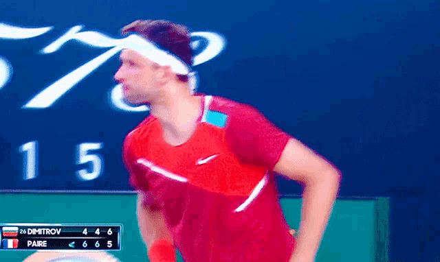 a man in a red shirt is standing in front of a scoreboard that says 15