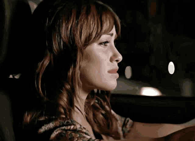 a woman is sitting in a car with her eyes closed