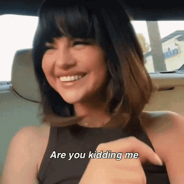 a woman in a black tank top is smiling and saying are you kidding me .