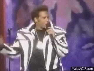 a man in a zebra print jacket is standing in front of a microphone on a stage .