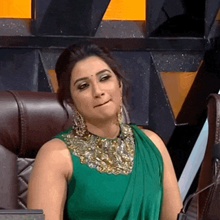 a woman in a green dress is sitting in a chair with her mouth open .