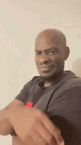 a man in a black shirt is making a funny face while holding his hands together .