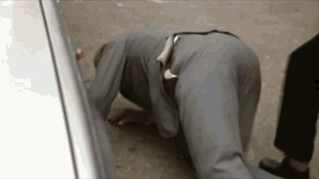 a man in a suit is kneeling on the ground near a car .