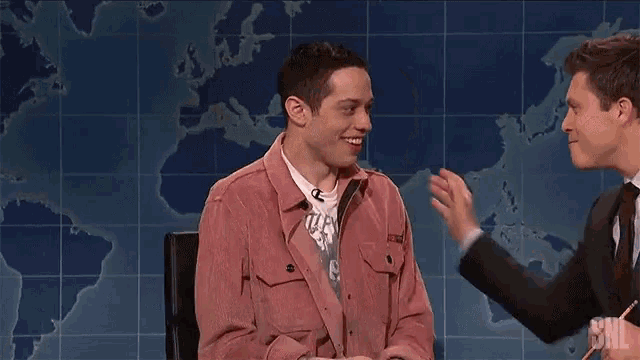 a man in a pink jacket is being interviewed by a man in a suit