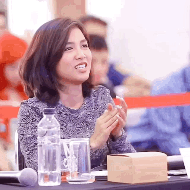 a woman sits at a table with a bottle of water and a box