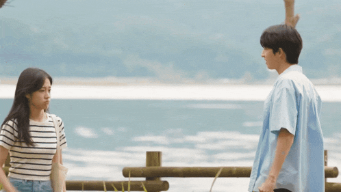 a man and a woman standing next to each other near a body of water