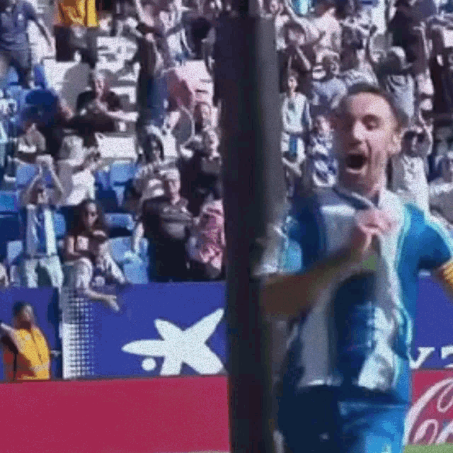 a man in a blue and white jersey is standing in front of a coca cola sign