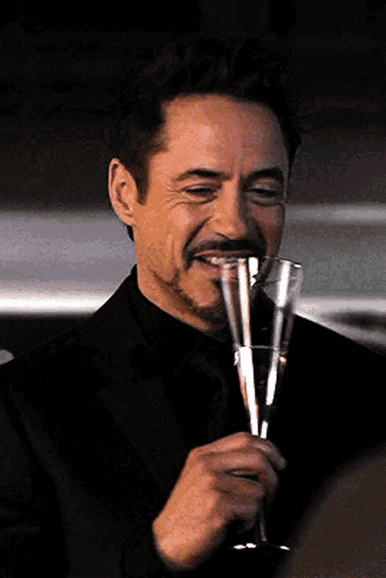 a man in a suit is holding a glass of champagne