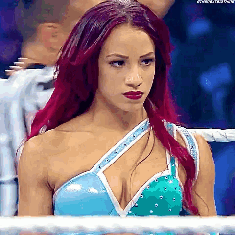 a woman with red hair is standing in a wrestling ring looking at the camera .