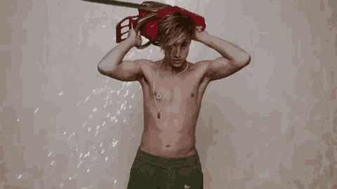 a shirtless man is holding a red object over his shoulder .