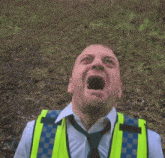 a man wearing a yellow vest and tie is screaming .