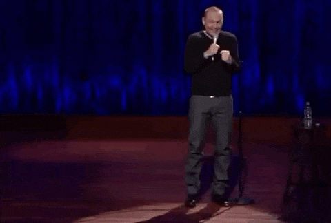 a man is standing on a stage holding a microphone and making a funny face .
