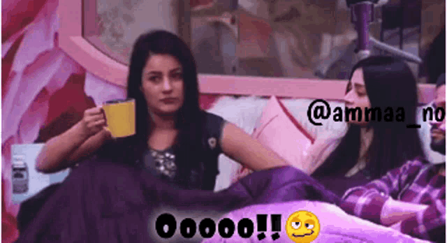a woman sitting on a bed holding a cup with a smiley face behind her that says oooo