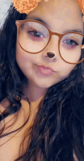 a girl wearing glasses and a flower crown on her head is taking a selfie .