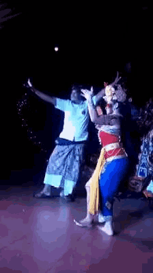 a group of people are dancing on a stage in a dark room