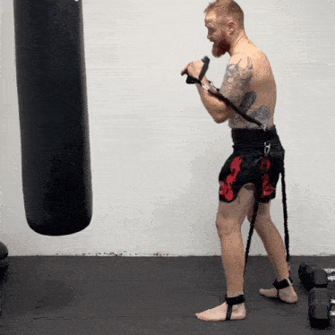 a man with a tattoo on his back is standing next to a punching bag