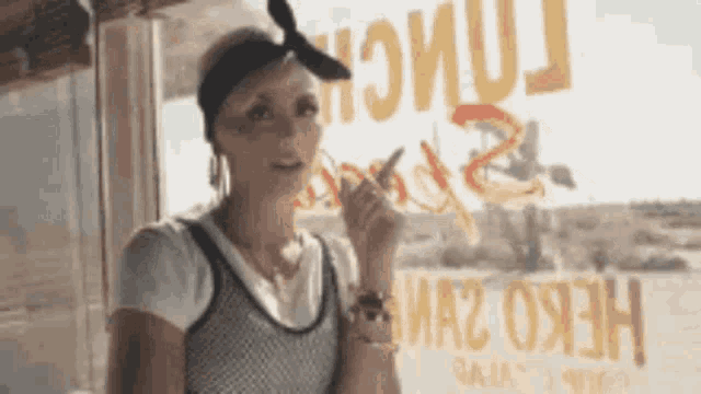 a woman is smoking a cigarette in front of a window that says ' a2 ' on it .