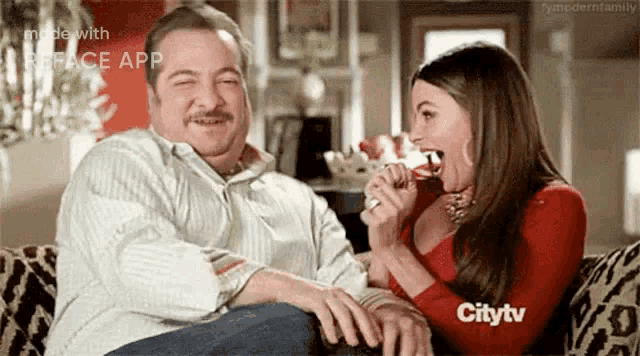 a man and a woman are sitting on a couch and the woman is eating something from the man 's hand .