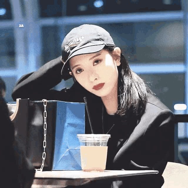 a woman wearing a black hat is sitting at a table with a cup of coffee .